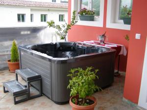 bañera de hidromasaje en un balcón con mesa y plantas en Hotel Wellness & Spa Angelo Gabriel, en Petrovac na Moru