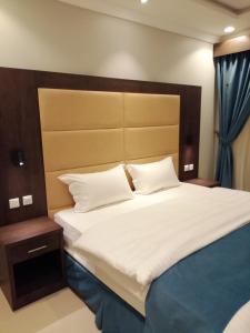 a bedroom with a large white bed with a wooden headboard at همم للوحدات السكنية - الحمدانية Al Hamdaniya in Jeddah