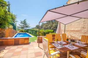 a patio with a table with an umbrella and a pool at Villa Montemar in Tossa de Mar