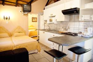 eine Küche und ein Schlafzimmer mit einem Bett und einer Theke in der Unterkunft Lalapanzi Hotel & Conference Centre in Bandelierkop
