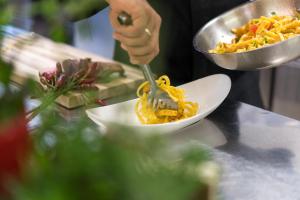 a person eating food with a fork in a bowl of food at Hotel Asterbel in Braies