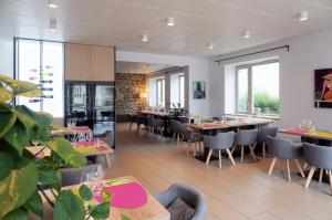 a dining room with tables and chairs and windows at Logis Hôtel Le Confluent in Pontaumur