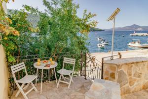 a table and chairs on a balcony with a view of the water at Apartments Bigovo Veljic in Tivat