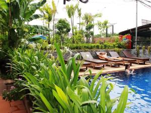 einen Pool mit Liegestühlen und Tischen in einem Resort in der Unterkunft Jasmine Lodge Siem Reap in Siem Reap