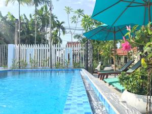 a swimming pool with chairs and an umbrella at The Moon River Homestay & Villa in Hoi An