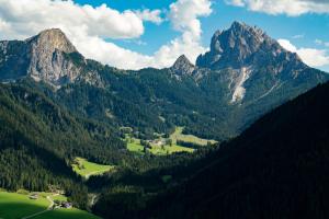 a mountain range with a green field and trees at Hotel Asterbel in Braies