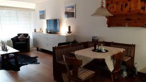 a living room with a table with chairs and a television at I dr Rehwiesa A13 in Arosa