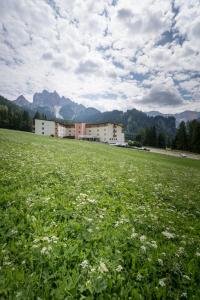 a field of grass with a building in the background at Hotel Asterbel in Braies