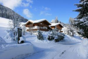 a house covered in snow in front of a road at Gasthof Schöntal in Werfenweng