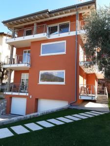 un edificio naranja con puertas blancas y patio en appartamentsandreis en Malcesine