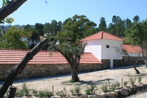 um edifício com telhados vermelhos e uma parede de pedra em Estabulo de Valinhas em Vitorino dos Piães