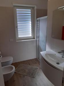 baño con lavabo y aseo y ventana en appartamentsandreis en Malcesine