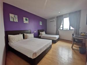 a bedroom with a large bed and a purple wall at Padungan Hotel in Kuching