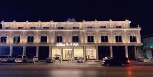 فندق قولد ان في الرياض: مبنى ابيض كبير به سيارات تقف في موقف للسيارات