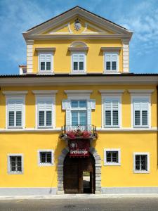 a yellow building with a clock on top of it at Grand Hotel Entourage - Palazzo Strassoldo in Gorizia