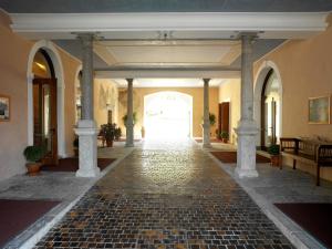 un couloir avec un sol en pierre et des colonnes dans un bâtiment dans l'établissement Grand Hotel Entourage - Palazzo Strassoldo, à Gorizia
