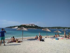 a group of people sitting on a beach with umbrellas at ApartHotel Viola in Pula