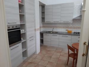 cocina con armarios blancos, fregadero y mesa en Casa Monti, en Scauri