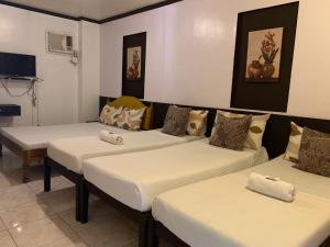 three beds in a room with white sheets at Center Parkway Pension House in Kalibo