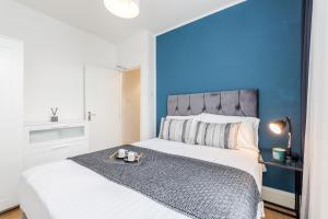 um quarto com uma parede azul e uma cama com uma bandeja em 2 Bedrooms Serviced Apartment ExCel Exhibition Centre, O2 Arena, Stratford Olympic City, Forest Gate, Central London em Londres