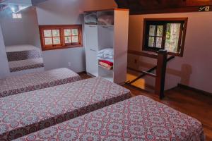 Cette chambre comprend deux lits, un bureau et deux fenêtres. dans l'établissement Pousada Villa Cantaloa, à Gramado