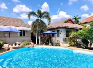 a man sitting in front of a house with a swimming pool at Nuch's Apple Guest House in Si Bun Ruang