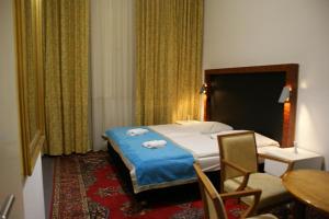 ベルリンにあるホテル ガルニ アベルナのベッド、テーブル、椅子が備わるホテルルームです。