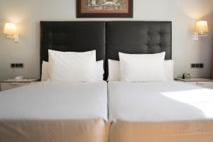 duas camas num quarto de hotel com almofadas brancas em Hotel Sercotel Tres Luces em Vigo