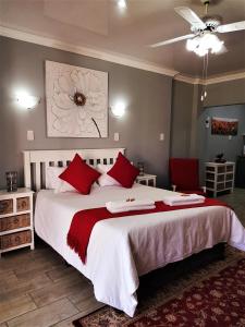 een slaapkamer met een groot bed met rode kussens bij Graceland Guesthouse in Potchefstroom