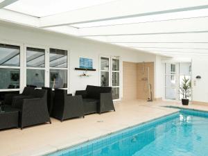 uma piscina com cadeiras pretas ao lado de uma piscina em 12 person holiday home in Eg em Åstrup