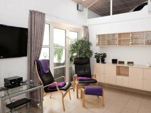 uma sala de estar com duas cadeiras e uma televisão em 12 person holiday home in Eg em Åstrup