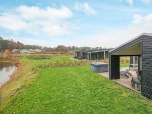 une maison avec une terrasse à côté d'une masse d'eau dans l'établissement 10 person holiday home in Glesborg, à Fjellerup Strand