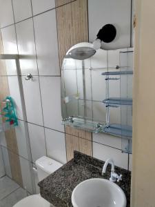 a bathroom with a sink and a toilet and a lamp at Casa Ubatuba Com Piscina in Ubatuba