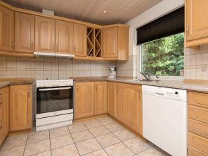 una cocina con armarios de madera y electrodomésticos blancos en 9 person holiday home in Bl vand, en Ho