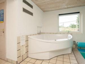 baño con una gran bañera blanca y ventana en 9 person holiday home in Bl vand, en Ho