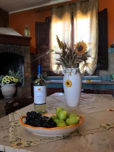 a bottle of wine and a plate of fruit on a table at La casetta degli ulivi con piscina in Menfi