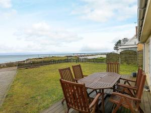 - une table et des chaises en bois sur une terrasse donnant sur l'océan dans l'établissement Three-Bedroom Holiday home in Frørup 3, à Tårup