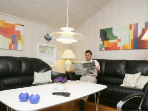 un hombre sentado en un sofá leyendo un periódico en 10 person holiday home in V ggerl se, en Bøtø By