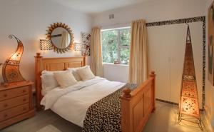 1 dormitorio con cama, ventana y espejo en Wilderness Beach Cottage, en Wilderness