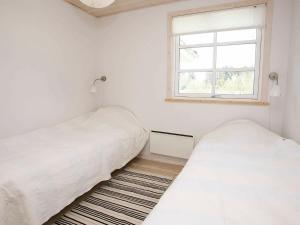 Three-Bedroom Holiday home in Brovst 31 في Brovst: سريرين في غرفة بيضاء مع نافذة