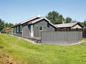 une maison avec une clôture devant une cour dans l'établissement Three-Bedroom Holiday home in Løkken 41, à Grønhøj