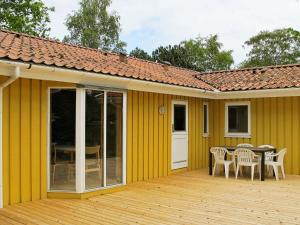 a yellow house with a table and chairs on a deck at Four-Bedroom Holiday home in Væggerløse 18 in Marielyst