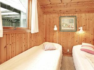 two beds in a room with wooden walls and a window at Three-Bedroom Holiday home in Idestrup 3 in Marielyst