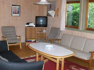 a living room with a table and chairs and a tv at Four-Bedroom Holiday home in Væggerløse 18 in Marielyst