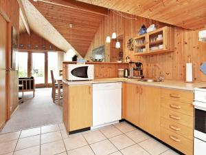 a large kitchen with wooden cabinets and a microwave at Three-Bedroom Holiday home in Idestrup 3 in Marielyst