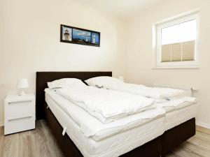 een slaapkamer met een bed met witte lakens en een raam bij Two-Bedroom Holiday home in Großenbrode 18 in Großenbrode