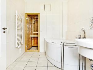 ein Badezimmer mit einer Badewanne, einem Waschbecken und einer Tür in der Unterkunft One-Bedroom Holiday home in Großenbrode 3 in Großenbrode