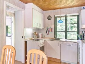 Snogebækにある6 person holiday home in Nexの白いキャビネット、シンク、食器洗い機付きのキッチンが備わります。