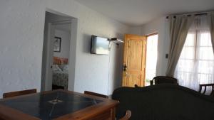 a living room with a table and a tv on the wall at Cabañas Aires del Bosque in Concón