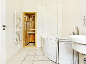 a bathroom with a tub and a sink and a door at One-Bedroom Holiday home in Großenbrode 5 in Großenbrode